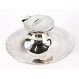An Edward VII silver Capstan inkwell, with a hinged lid enclosing a milk glass liner, on a circular
