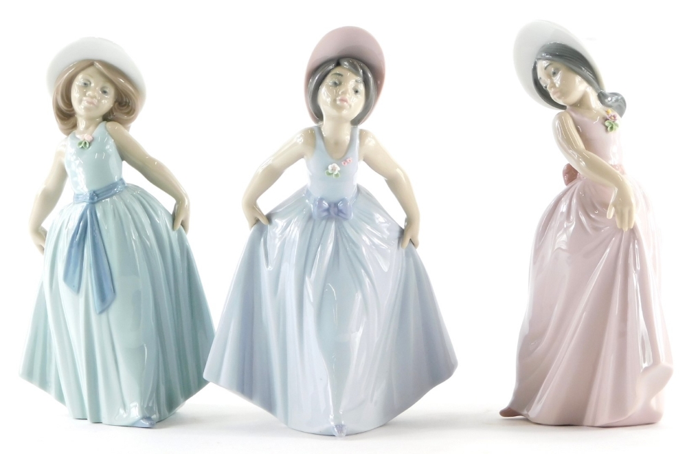 Three Lladro porcelain figures of girls wearing flowing dresses, in shades of blue, green and pink,