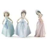 Three Lladro porcelain figures of girls wearing flowing dresses, in shades of blue, green and pink,