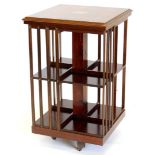 A mahogany revolving bookcase, the square top inlaid with a central patera within a satin wood cross