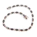 A silver tennis bracelet, set with oval mystic topaz stones, with silver brakes and side and double