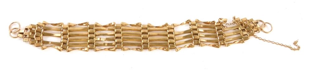 A gate bracelet, of six bar linked design with safety chain, yellow metal, unmarked, 18cm long, 11.6