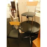 A black circular top kitchen table, on a metal base, and two associated chairs.