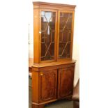 A freestanding corner cabinet, the top with astragal glazed doors, above two hinged doors.