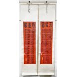 A cased set of two Chinese scroll pictures, each with a red rectangular panel depicting various symb