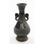 A Chinese bronze vase, on flared foot, with everted neck and two ear handles, the low relief decorat