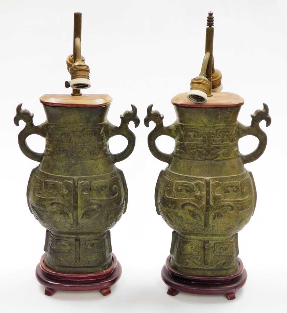 A pair of Eastern bronze twin sconce table lamps, each with relief decoration in archaic style, on s