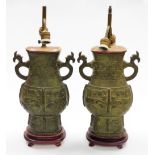 A pair of Eastern bronze twin sconce table lamps, each with relief decoration in archaic style, on s