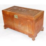 A Chinese camphorwood chest, the top carved in relief with a party scene set in a landscape, brass l