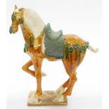 A Chinese terracotta horse in Tang style, decorated in green and orange glaze on a rectangular base,