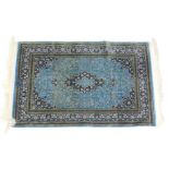 A Qum Arsalani silk rug, decorated with floral motif against a turquoise ground within a blue border