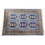 A Pakistani blue ground rug, decorated with six medallions, each containing three guls, within a rep