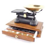 A set of brass and cast iron kitchen scales, raised on a twin handled mahogany base, with drawer ope