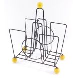 A 1960's atomic style magazine rack, with four wire work divisions, on yellow feet, 30cm long.