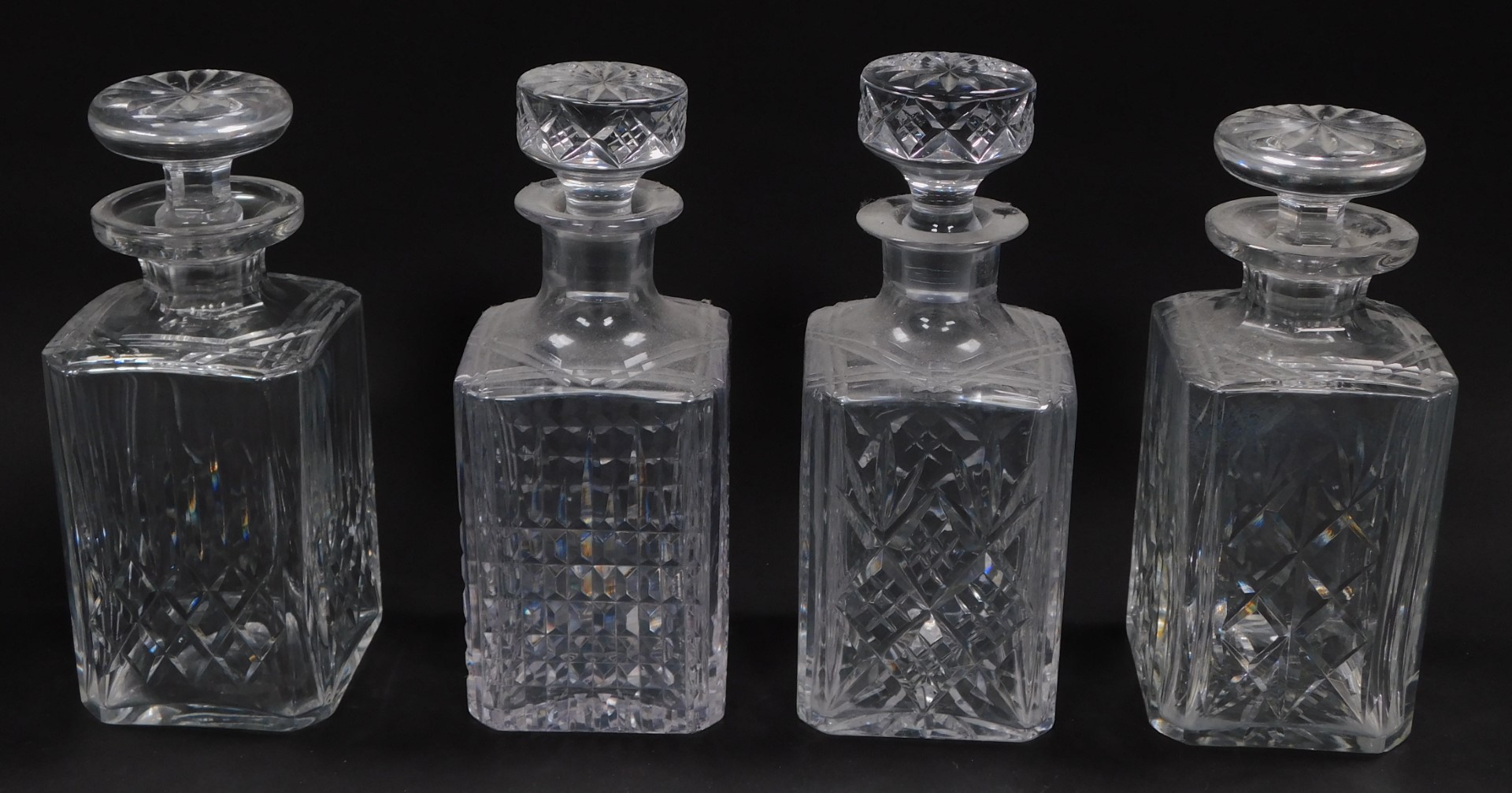 Four cut glass decanters, of rectangular section, each with stoppers, some unmatched.