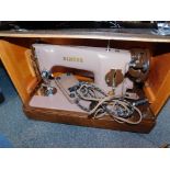 A cased Singer sewing machine, with foot pedal, in a pale pink colouring, in a snakeskin finish carr