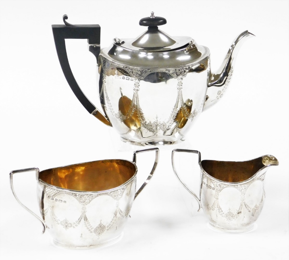 A George V silver Neo Classical design three piece tea service, bright cut decorated with bow drops,