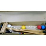 A cased croquet set, in a cardboard sleeve with wooden ends, comprising four mallets, stakes, and va