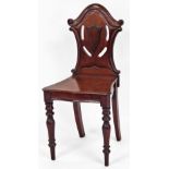 A Victorian mahogany hall chair, with pierced shield back with scroll top, on shaped seat, and turne