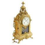 A French cast brass mantel clock, the domed top with a fleur de lis finial and applied with two drag