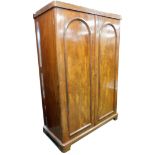 A Victorian mahogany wardrobe, with rounded cornice above two doors with arched top on bun feet, 200