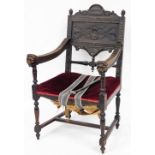 A 19thC Gothic carved oak hall chair, with a panel back and lion mask handles, on red draylon seat,