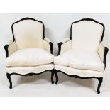 A pair of French style armchairs, with scroll fluted carved arms and cabriole legs, upholstered in a