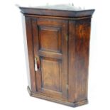 A George III oak corner cabinet, with two panelled door on moulded cornice, with brass key plate, 10