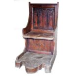 A stained pine Gothic style throne chair, the two seat back with carved detailing, on a later base,