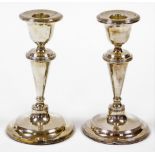 A pair of Edward VII silver dwarf candlesticks, each with a taper stem and stepped base with weighte