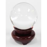 A witch's crystal ball, on hardwood stand, 20cm high.