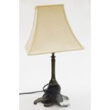 A metal table lamp, with scroll leaf base and cream shade.