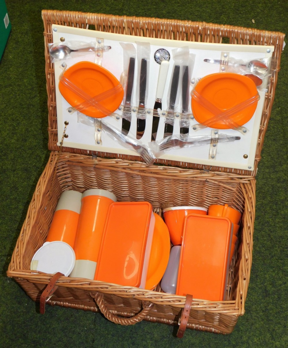 A wicker picnic basket and contents, with orange plastic wares, marked Travel With Safety.