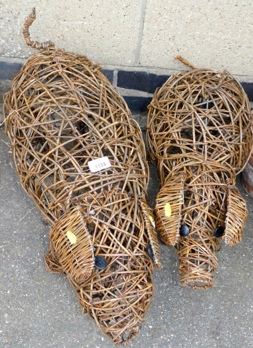 Two wicker garden pigs, the largest 66cm long, the smallest 58cm long, and each approximately 32cm h