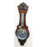 An oak cased aneroid barometer, with winter/summer dial and carved frieze.