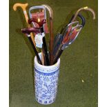 A blue and white stick stand and various walking sticks.