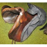 A leather riding saddle and cover.