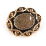A Victorian memorial brooch, the central blackened panel with inter weaved locket of hair, in a gold
