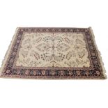 A Persian style rug, with a design of flowers on a cream ground with one wide and multiple borders,