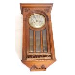 An early 20thC oak cased wall clock, with bevelled glass and silvered dial, 70cm high.