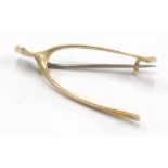 A 15ct wishbone shaped brooch, with base metal pin, 3.3g all in.