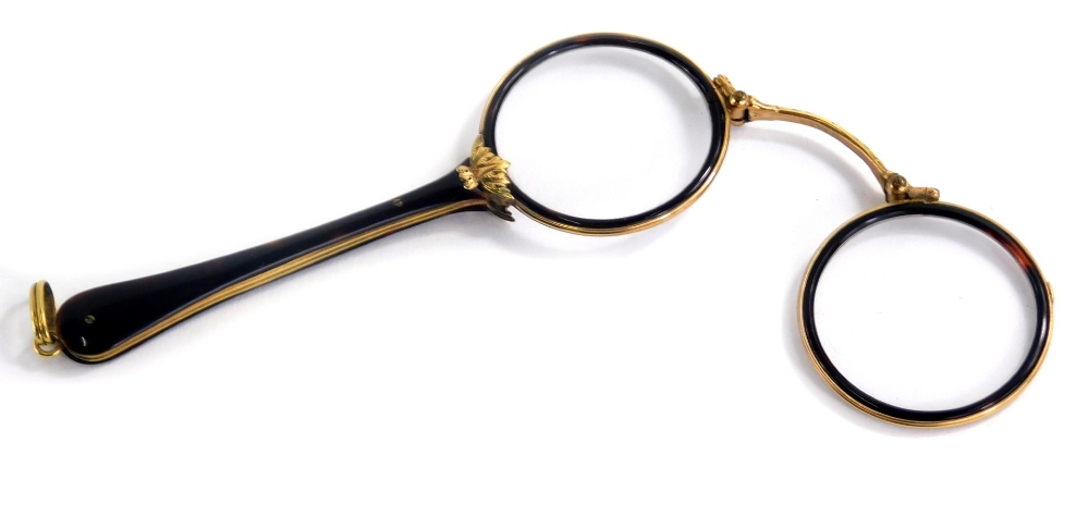 An early 20thC tortoiseshell and gold coloured metal lorgnette, each with a tapering handle cast wit