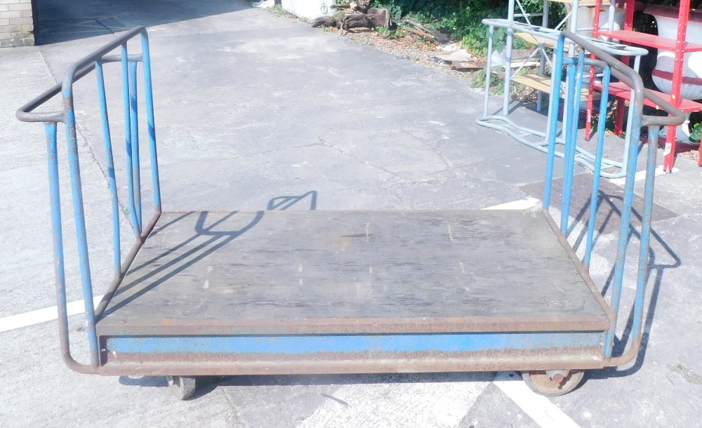 A blue painted tubular metal industrial four wheel trolley.