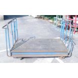 A blue painted tubular metal industrial four wheel trolley.