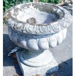 A composition urn, with part fluted decoration on a square base.