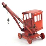 An early 20thC child's tin plate crane, of shaped form with articulated top and hook on four wheels,