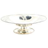 A George V silver dish, of shaped oval form, with part pierced body, on a squat stem and oval foot,