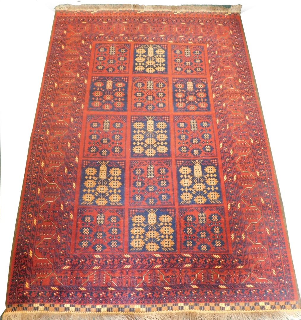 A Balouch type rug, with a design of medallions, in navy and cream on a red ground with multiple bo