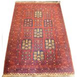 A Balouch type rug, with a design of medallions, in navy and cream on a red ground with multiple bo