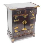 A Chinese hardwood and brass side cabinet, with a shaped top above two frieze drawers and two doors,